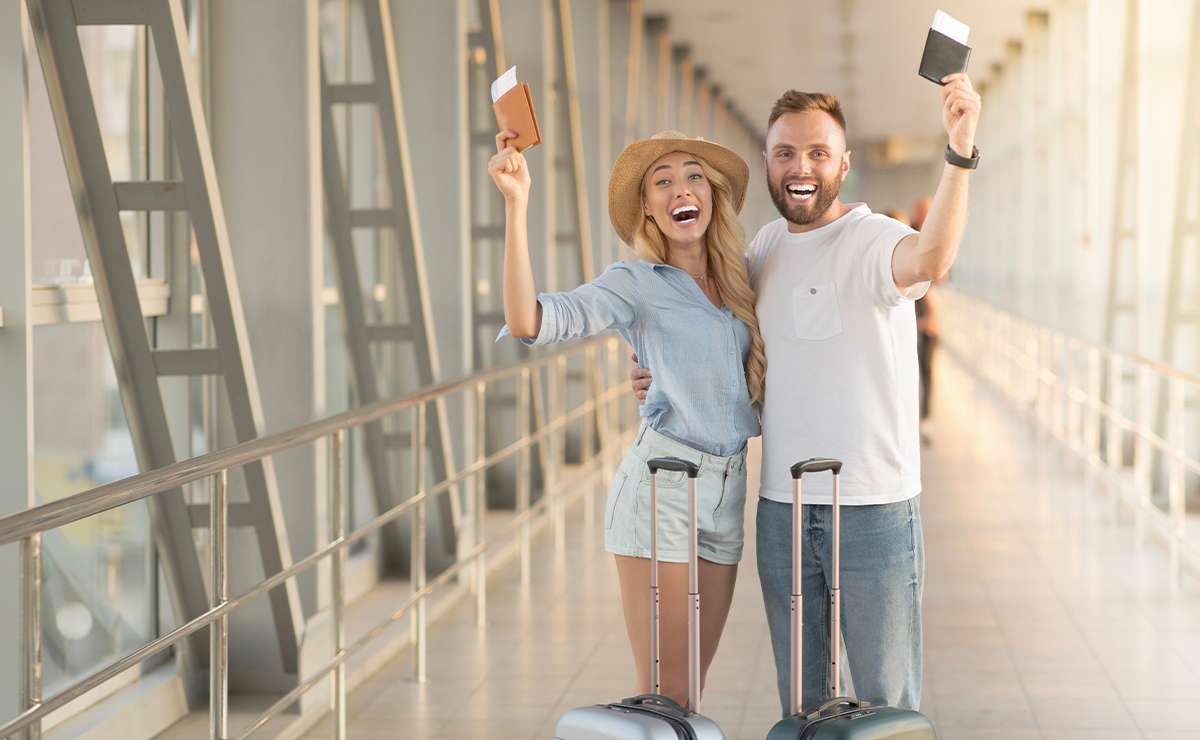 Coppia giovane in aeroporto con valigie trolley
