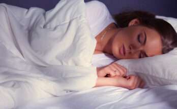 Donna addormentata in un letto con lenzuola bianche