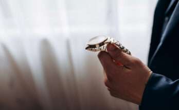 Uomo elegante osserva un orologio da polso di lusso con cinturino in metallo dorato