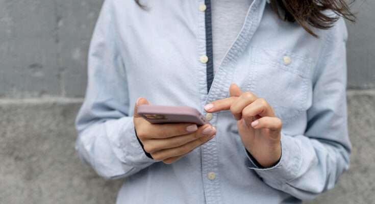 donna tiene in mano telefono mentre clicca sullo schermo