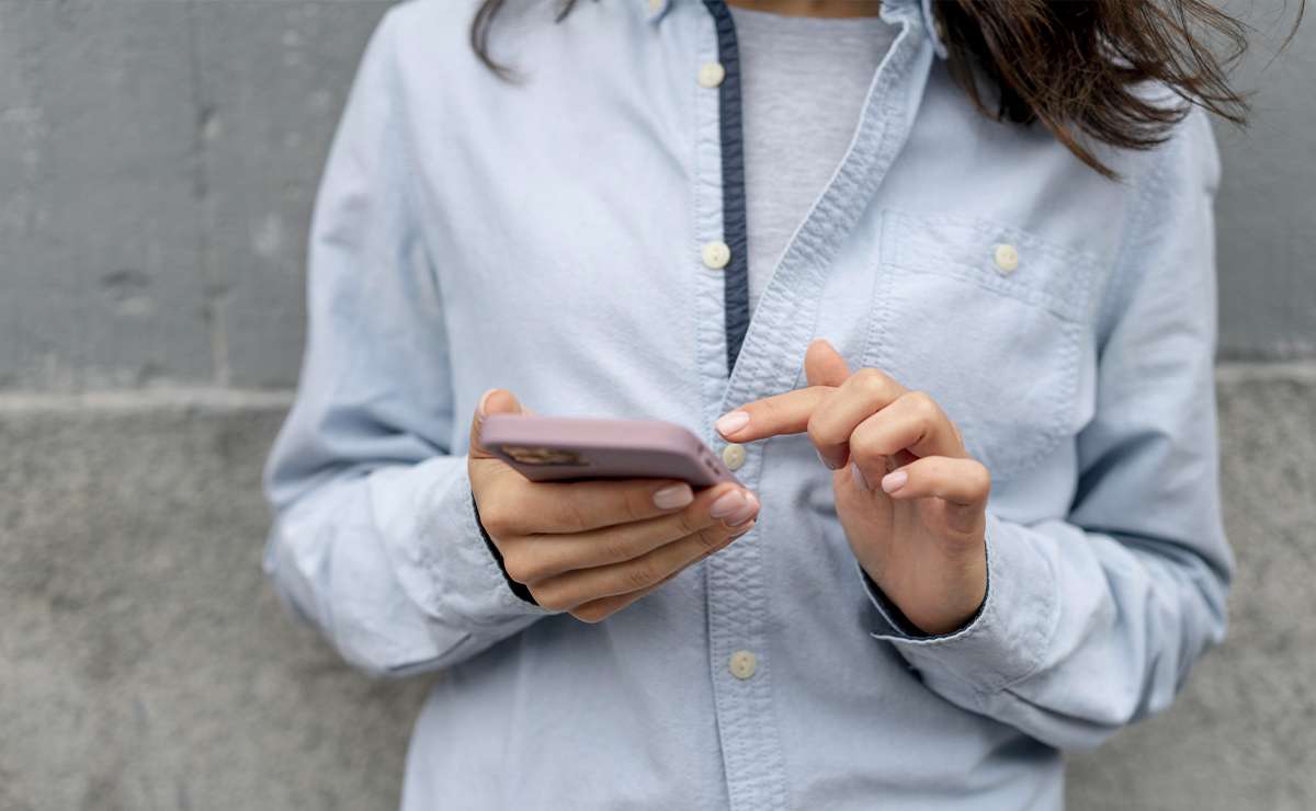 donna tiene in mano telefono mentre clicca sullo schermo